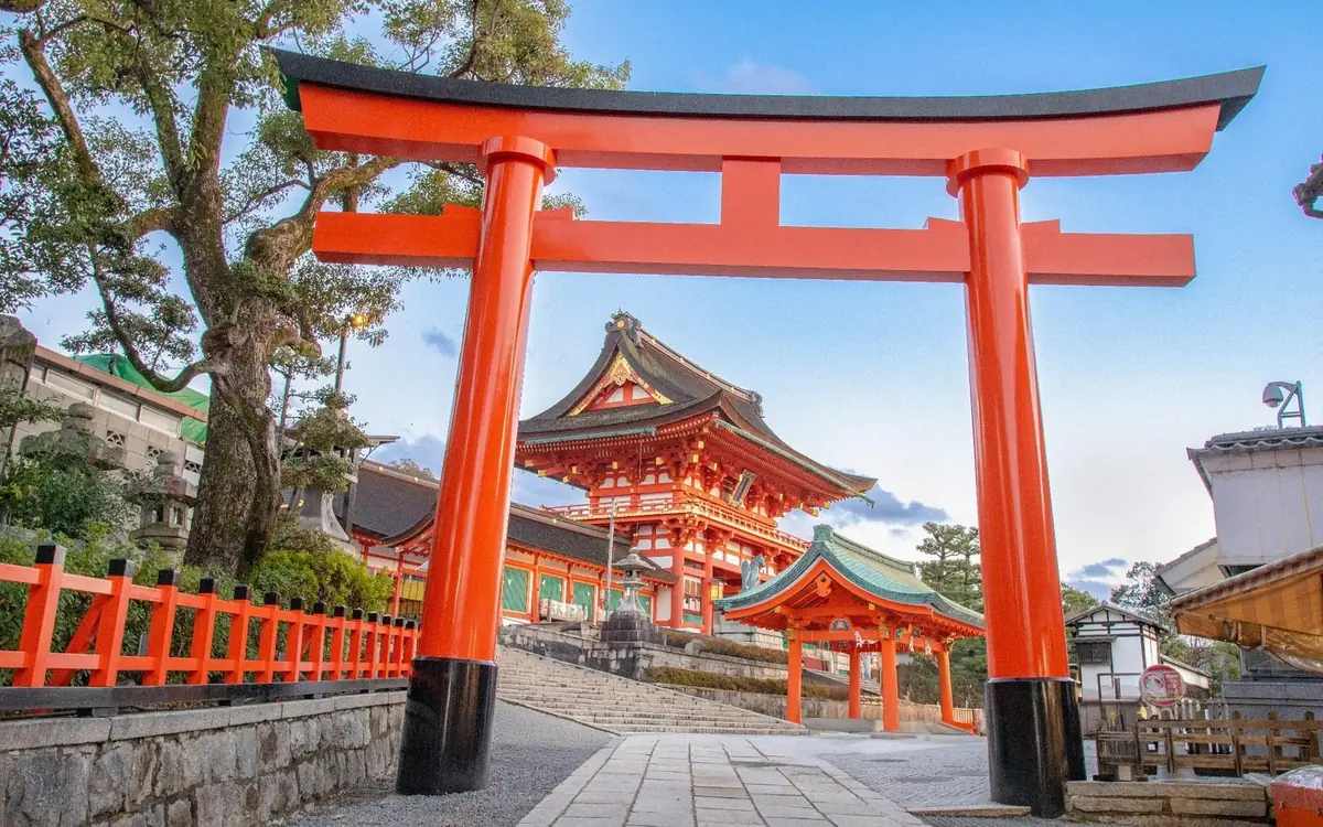 A large vermilion torii gate against a blue sky at Fushimi Inari