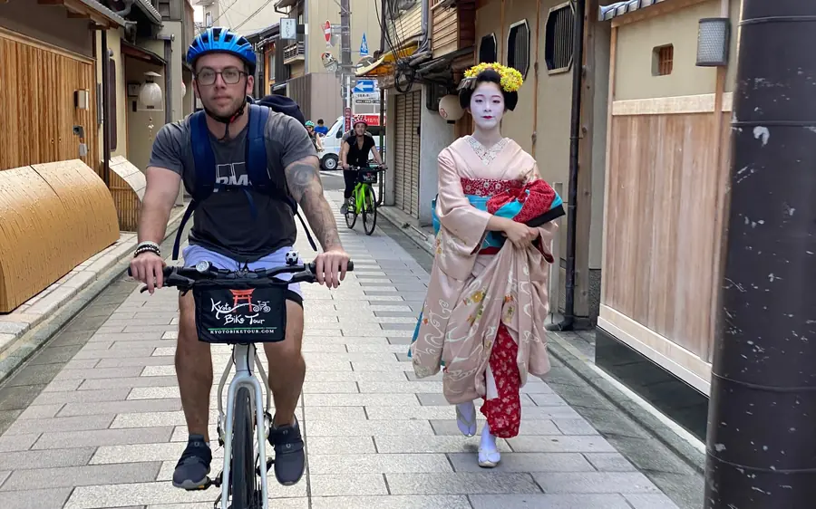 A cyclist on a Kyoto lane passing a woman in traditional dress