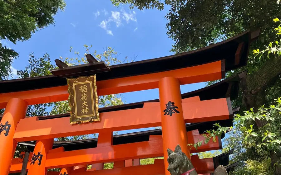 Torii gates and a stone fox guarding the path at Fushimi Inari