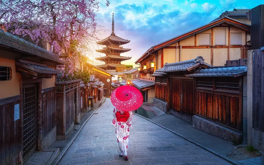 A lantern-lit Kyoto street of wooden houses below a pagoda